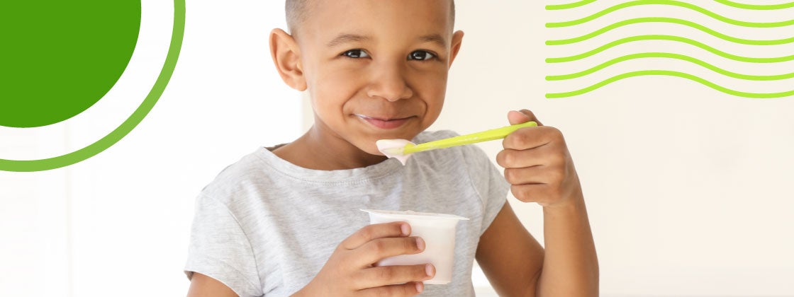 Niño comiendo alegre un yogurt con una cuchara