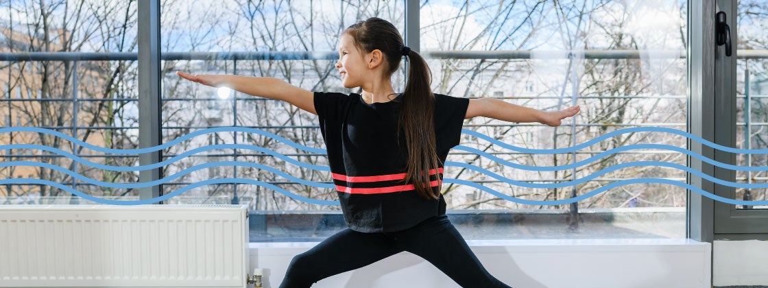 niña haciendo postura del guerrero de yoga en su casa