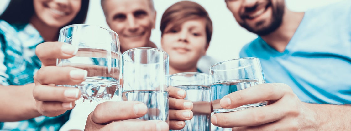 Familia sonriente bebiendo agua en vasos