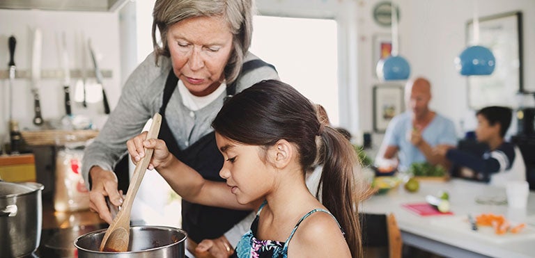 Niña junto a su abuela preparando recetas en el fogón 