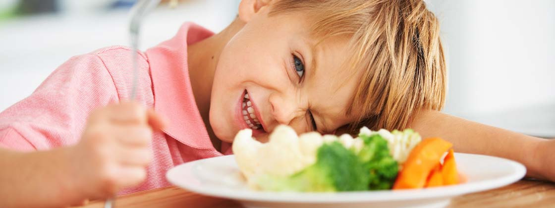 Niño alimentándose con un plato de vegetales
