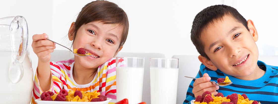 Niños comiendo un desayuno que contiene vitaminas que ayudan al desarrollo del cerebro