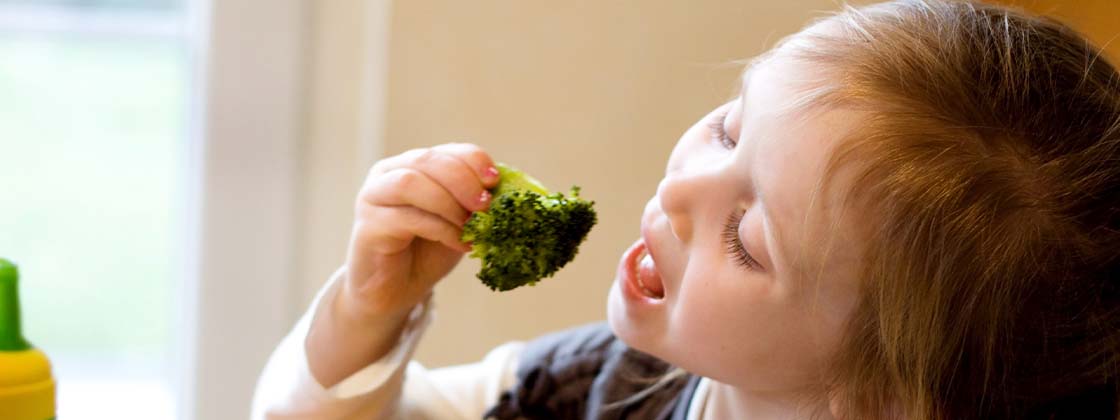 Niña comiendo brócoli como un hábito alimenticio