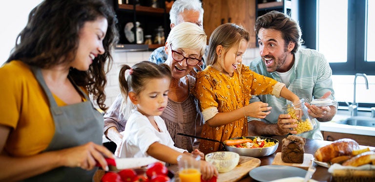 Papás, abuelos y niñas preparan recetas juntos mientras comparten en familia