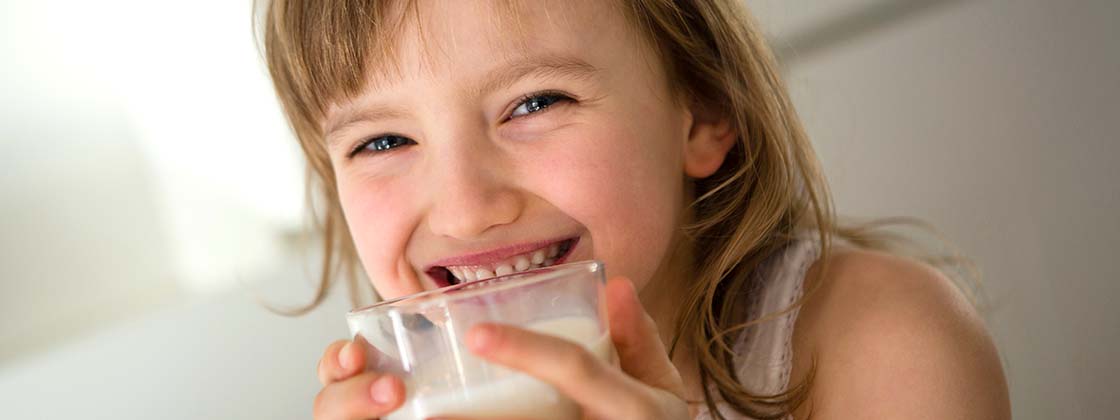 Niña tomando leche que aporta vitamina A