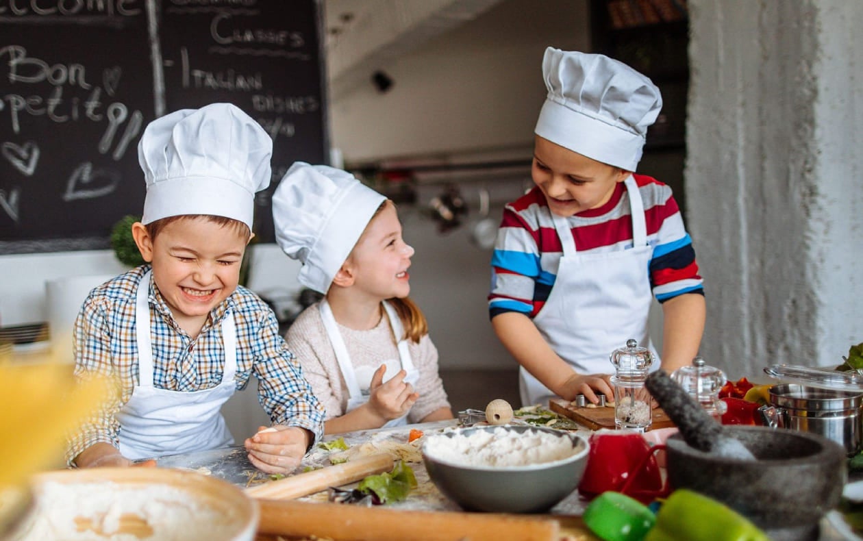 Niños aprenden habilidades socioemocionales cooperando y socializando en la cocina