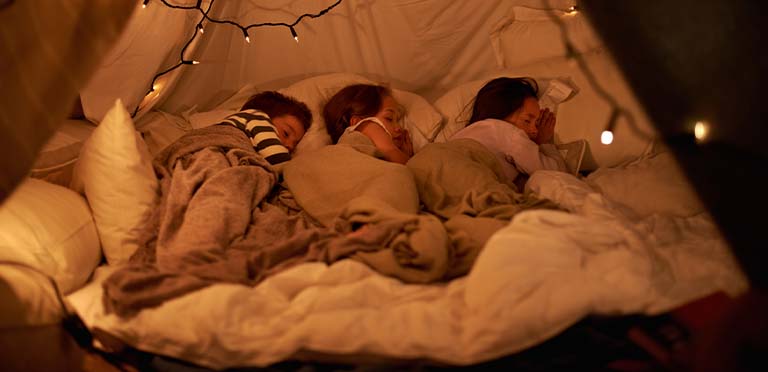 Tres niños duermen bien en una carpa improvisada para obtener un descanso completo